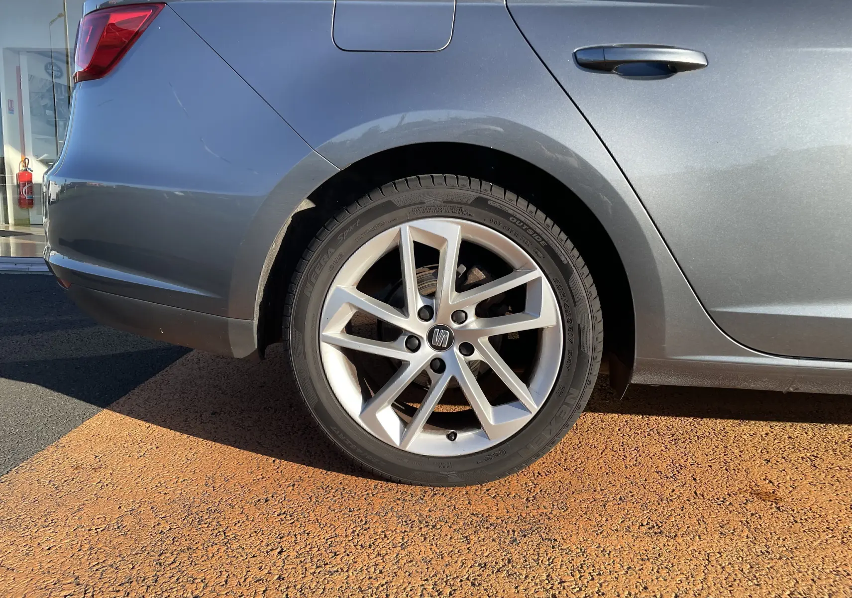 Gros plan sur la roue arrière droite d'une SEAT LEON ST gris métallisé avec jante alliage à 5 branches doubles.