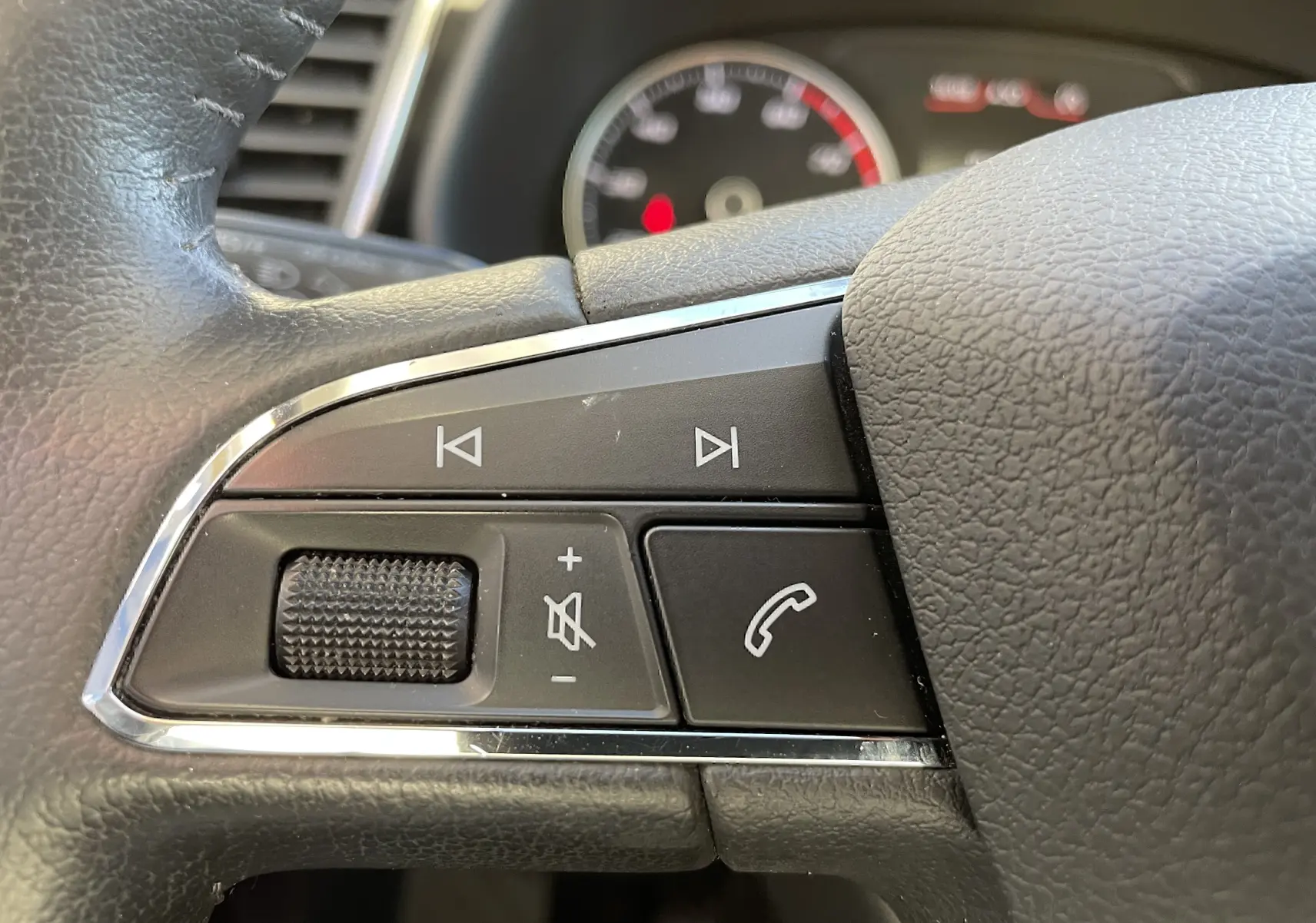 Gros plan sur les commandes audio et téléphone au volant en cuir noir du SEAT LEON ST gris 2013.