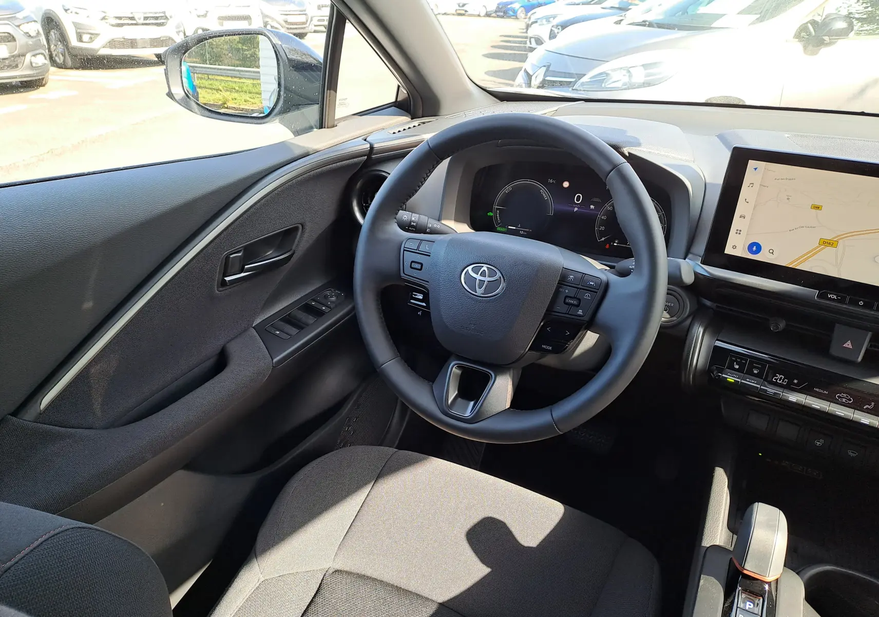 Vue intérieure côté conducteur du Toyota C-HR gris minéral 2025, avec volant multifonction et écran tactile de navigation.