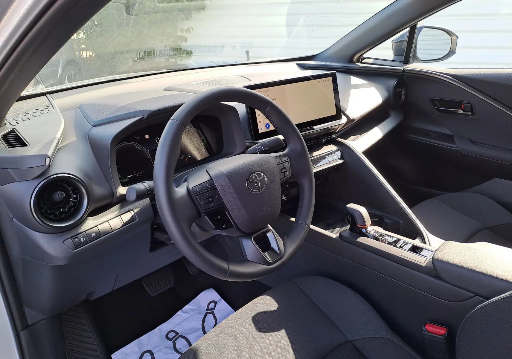 Intérieur du Toyota C-HR II STYLE 1.8 Hybrid 2025, vue côté conducteur sur le tableau de bord et la console centrale noire.