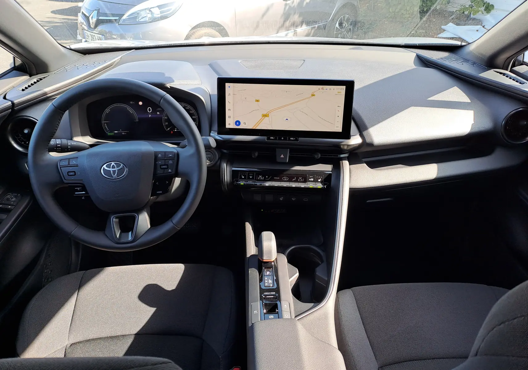 Vue intérieure du tableau de bord du Toyota C-HR gris minéral 2025, avec écran tactile central et volant multifonction.