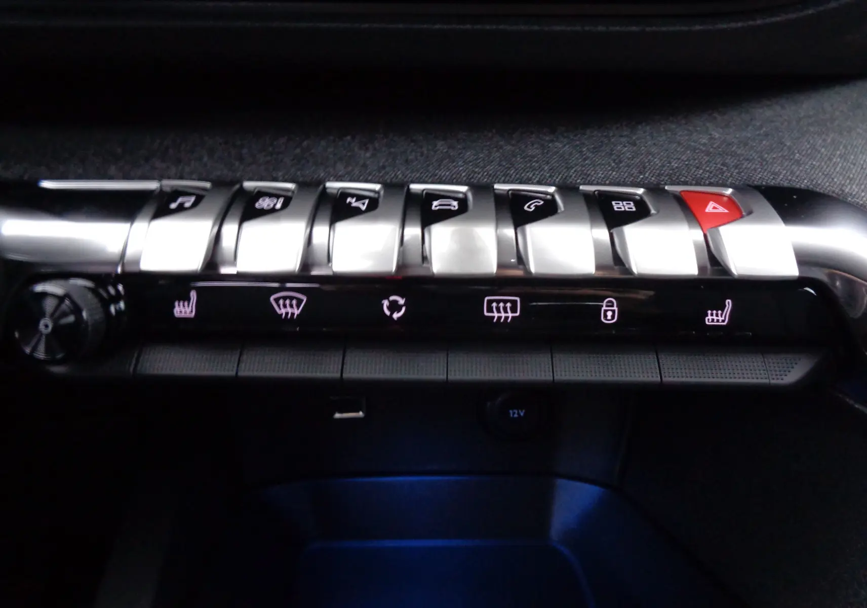 Gros plan sur la rangée de boutons argentés et noirs du tableau de bord du Peugeot 3008 noir, avec commandes de climatisation et sièges chauffants.