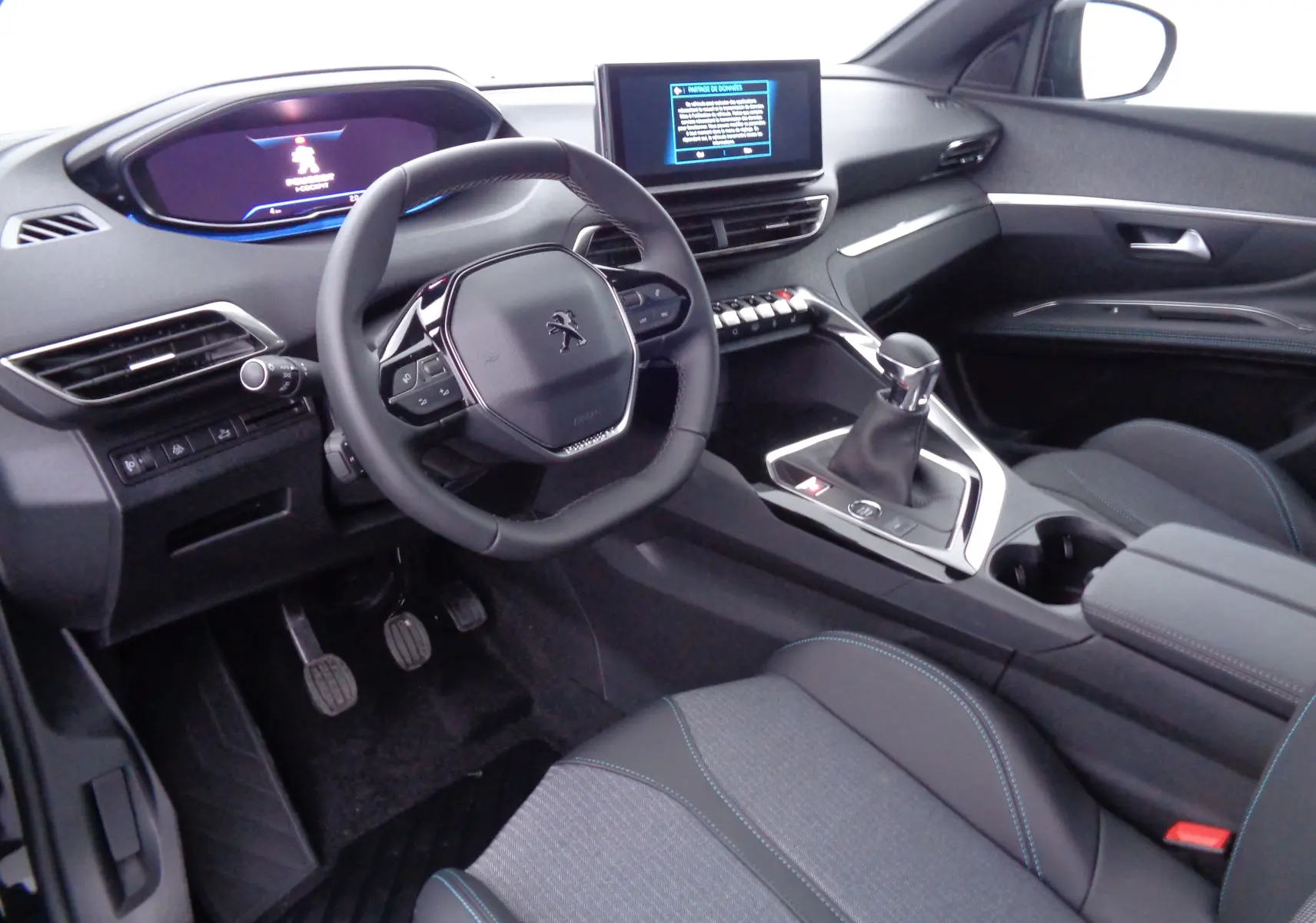 Intérieur du Peugeot 3008 2023 en noir, vue côté conducteur montrant volant compact, écran tactile et levier de vitesses manuel.
