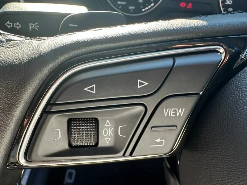 Gros plan sur les commandes au volant à droite de l'Audi Q2 35 TFSI 150ch S line 2023 en Noir Mythic métallisé.