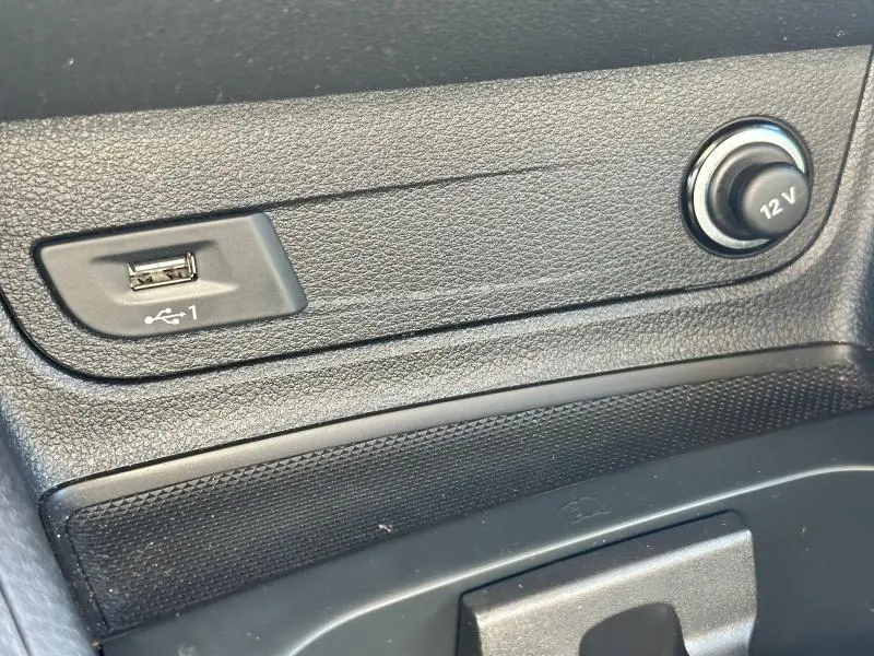 Prise USB et prise 12V en gros plan sur la console centrale d'un Audi Q2 noir Mythic métallisé 2023.