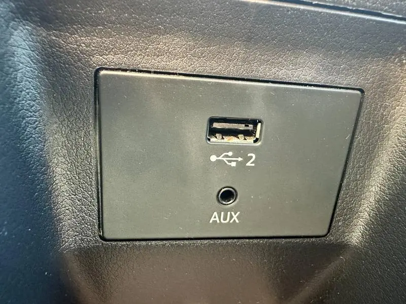 Prise USB et port AUX en gros plan dans l'habitacle de l'Audi Q2 35 TFSI S line 2023 noir Mythic métallisé.