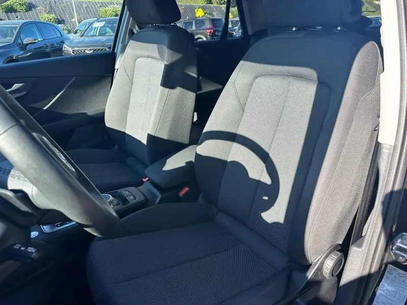 Vue intérieure côté conducteur de l'Audi Q2 35 TFSI S line 2023 avec sièges tissu noirs et console centrale visible.