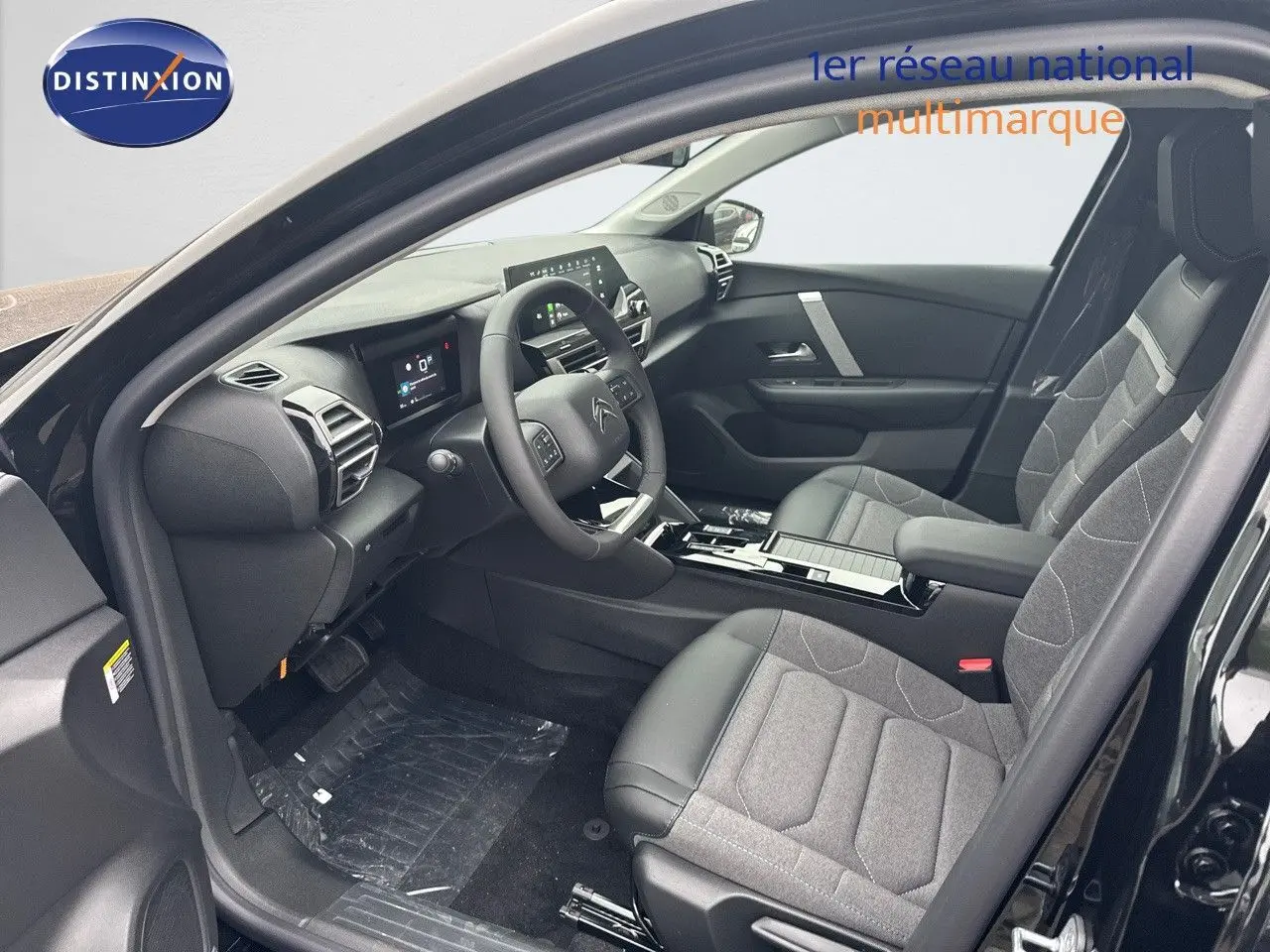 Intérieur avant droit d'une Citroën C4 noire métal 2024, sièges tissu et cuir gris, tableau de bord moderne avec écran tactile.