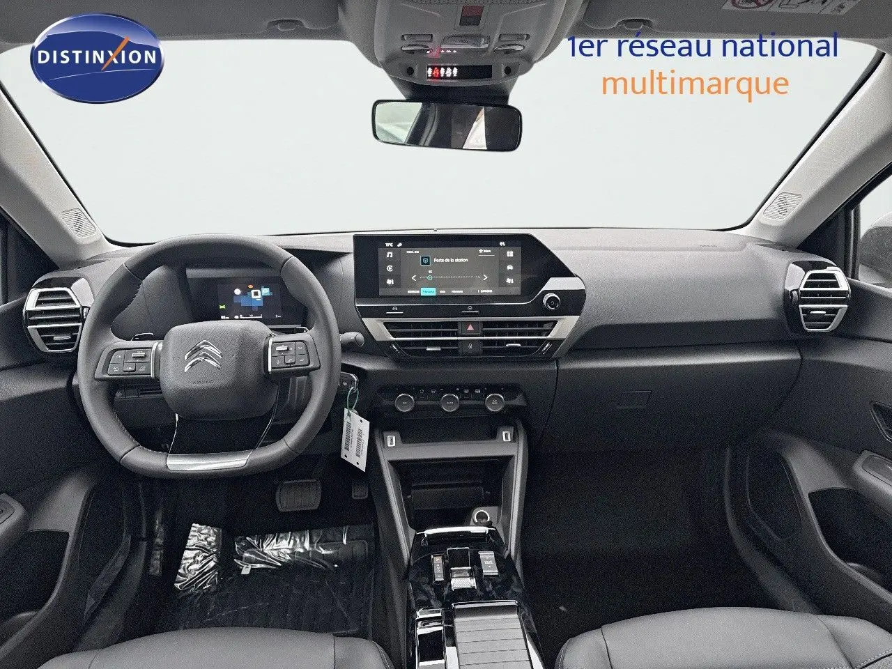 Vue intérieure avant du tableau de bord et volant noir de la Citroën C4 2024 avec écran tactile central et commandes au volant.
