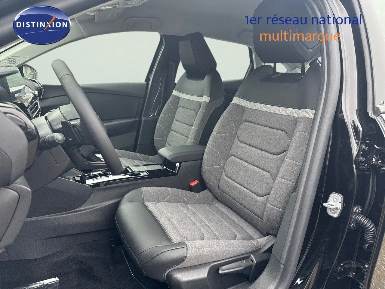 Vue intérieure côté conducteur d'une Citroën C4 2024 noir métal, sièges tissu gris et cuir noir avec console centrale moderne.