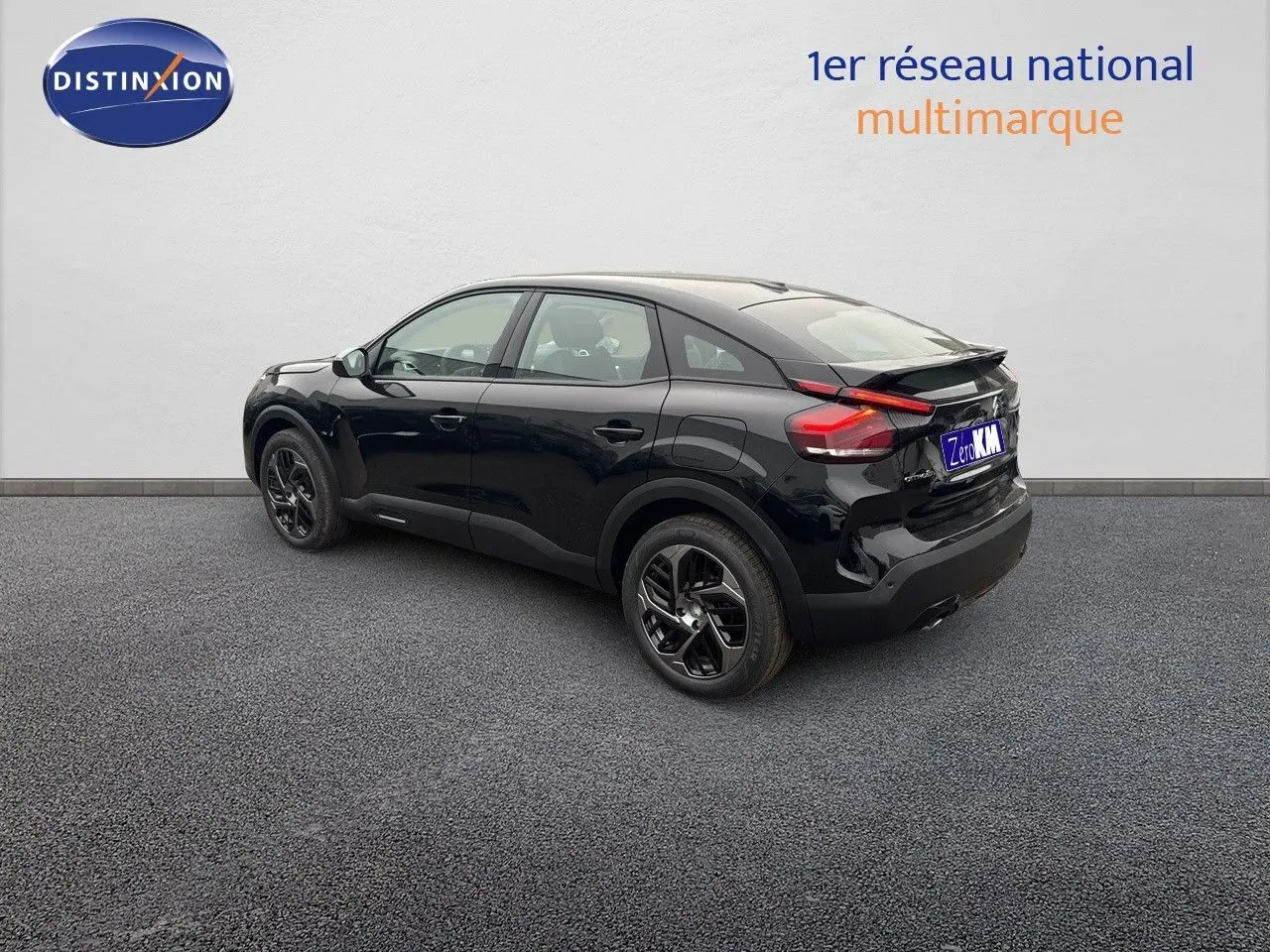 Vue 3/4 arrière droite d'une Citroën C4 noire métal 2024 avec jantes noires et feux arrière LED distinctifs.