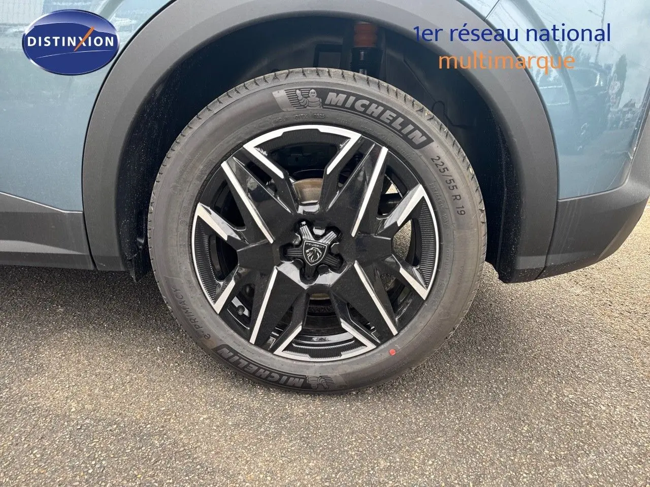 Gros plan sur la roue avant droite du Peugeot 3008 Hybrid 136ch GT bleu Ingara métal avec jante noire et argentée.