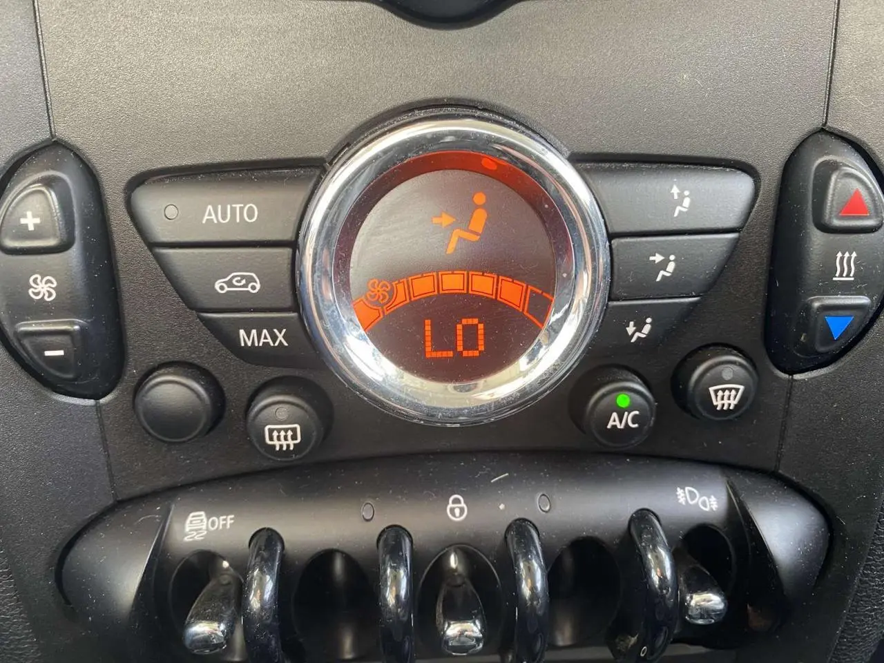 Gros plan sur la commande de climatisation automatique du MINI Countryman gris clair, affichage digital orange indiquant "LO".