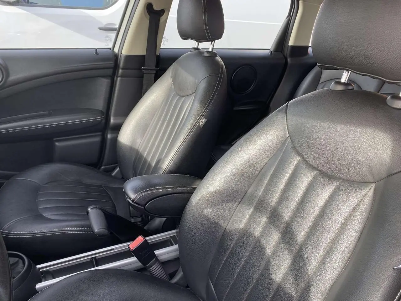 Vue rapprochée des sièges avant en cuir noir d'une MINI Countryman 2015, soulignant le détail des coutures et l'accoudoir central.