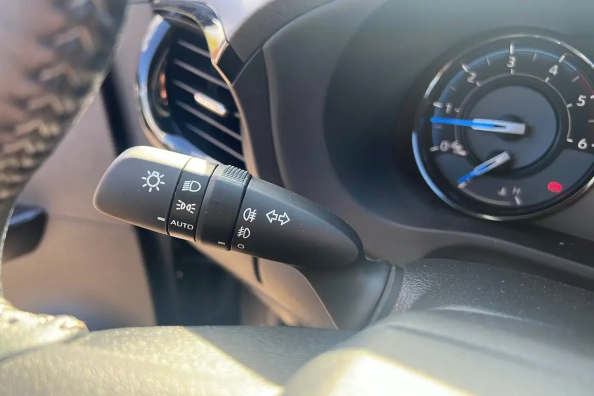Gros plan sur la commande des phares et clignotants à gauche du volant du Toyota Hilux Invincible gris atlas 2025.