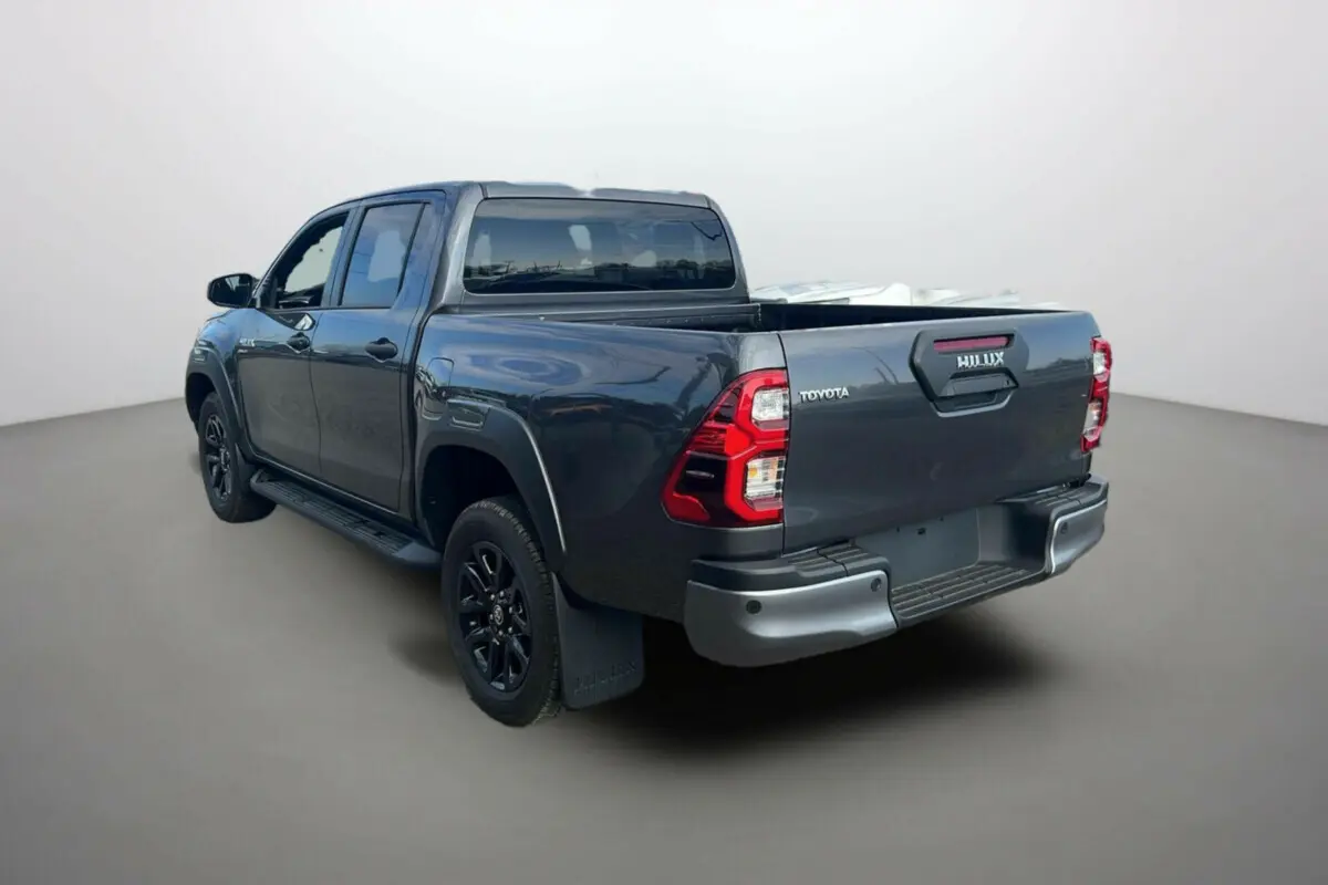 Toyota Hilux 4x4 gris atlas en 3/4 arrière droit, avec benne ouverte et jantes noires distinctives.