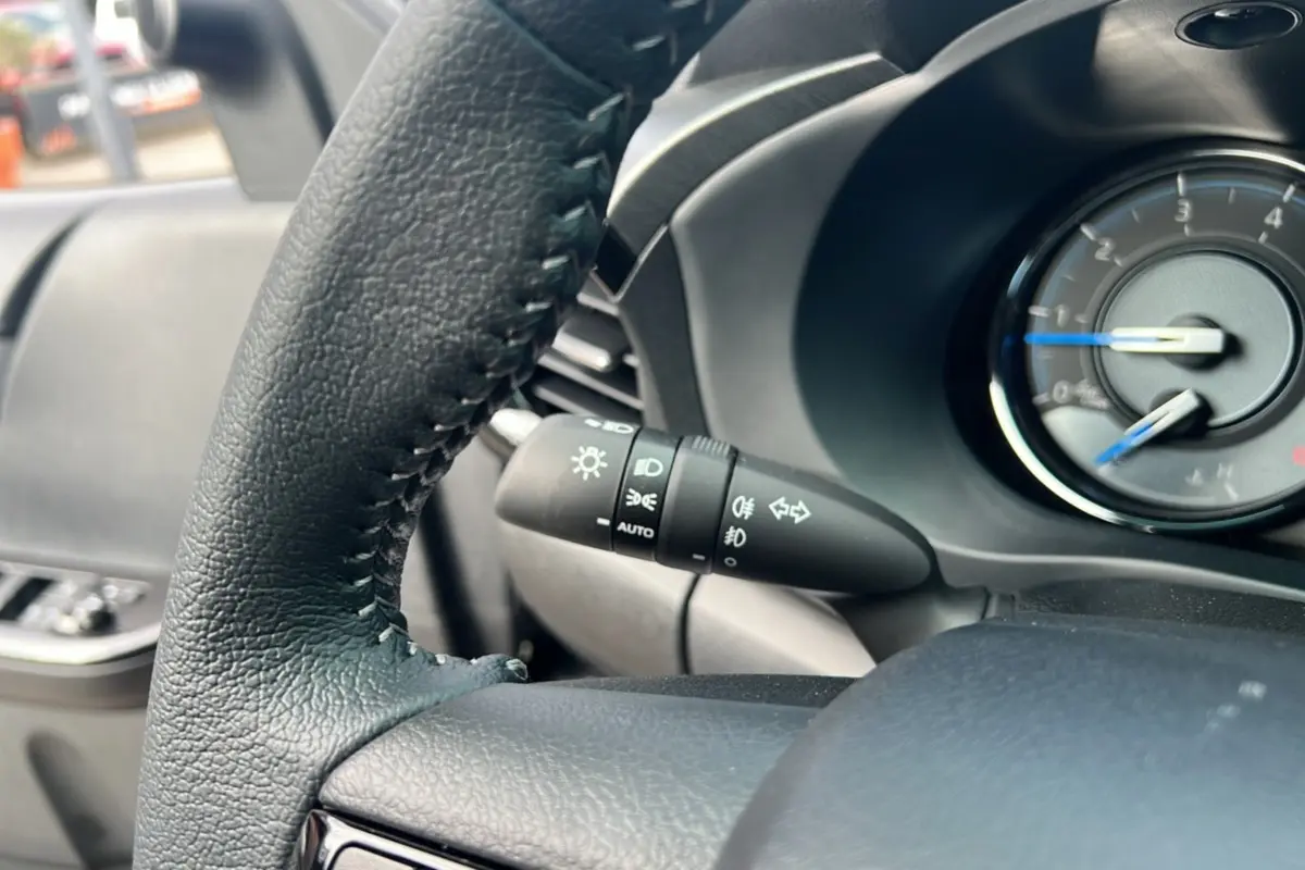Gros plan sur le volant et la manette des feux du Toyota Hilux 2025 gris atlas, tableau de bord partiel visible.