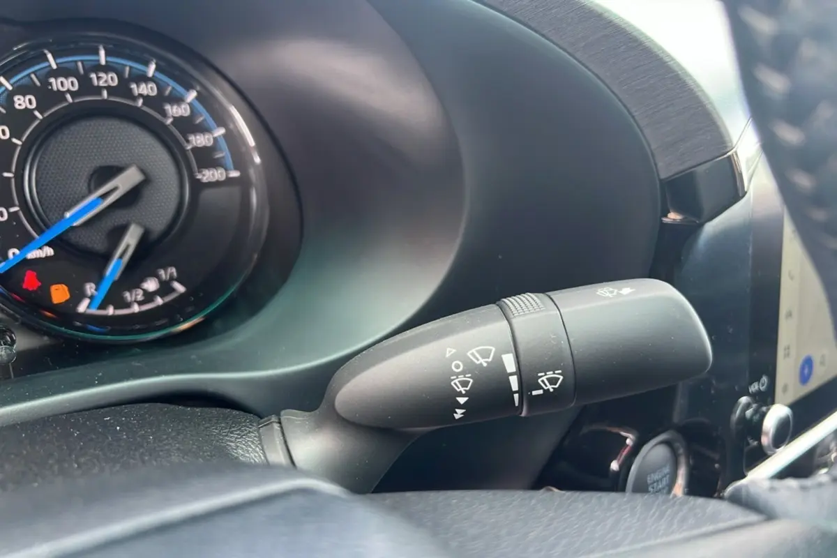 Gros plan sur le commodo d'essuie-glace et le compteur du Toyota Hilux 2025 gris atlas, intérieur moderne et fonctionnel.