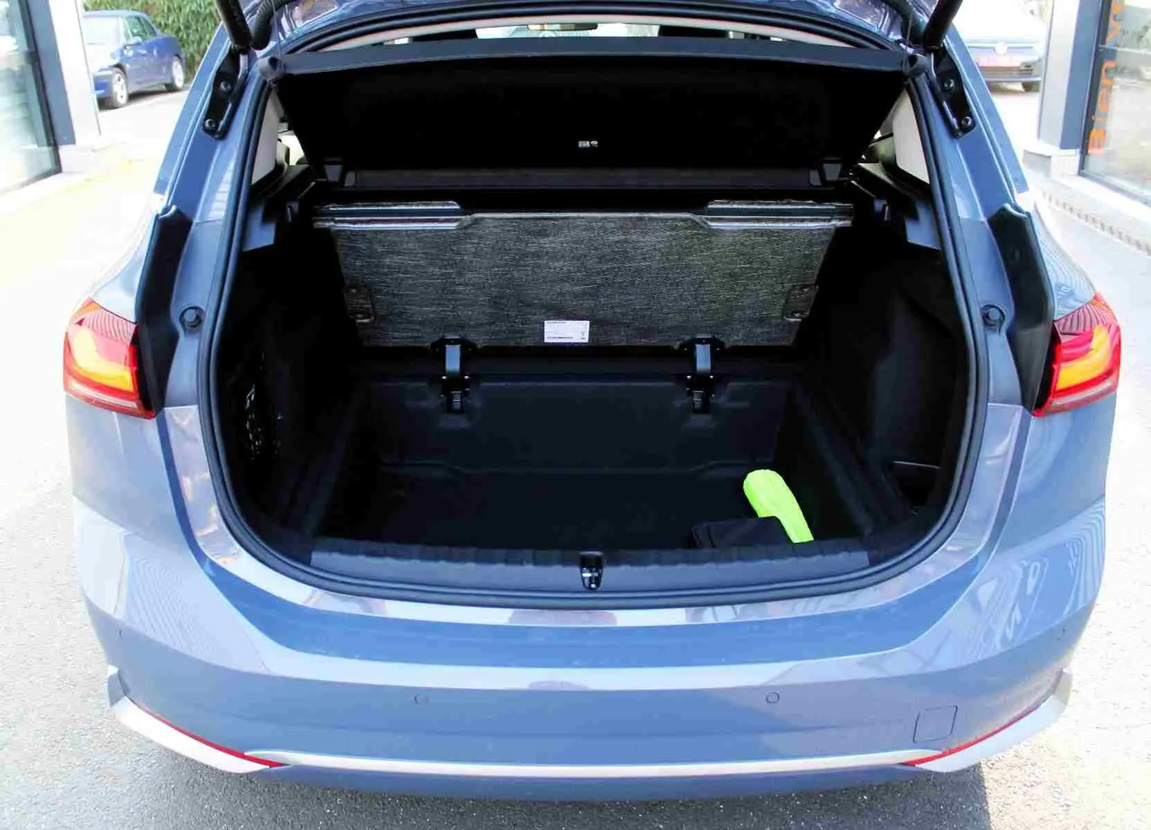 Coffre ouvert vu de l'arrière d'une BMW Série 2 Active Tourer gris Nardo métal, avec un objet vert à l'intérieur.