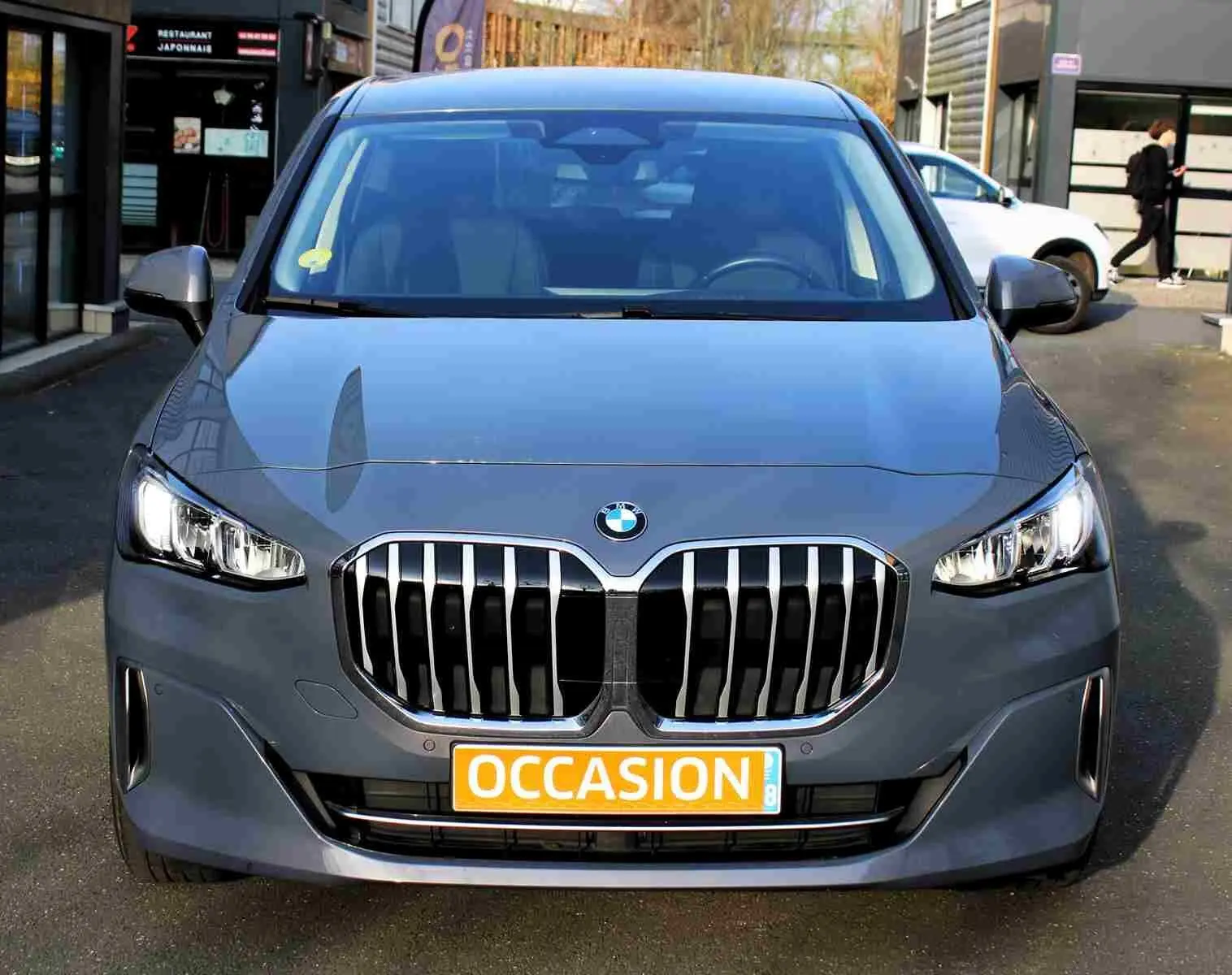 Vue frontale d’une BMW Série 2 Active Tourer gris Nardo métal avec calandre imposante et phares allumés.