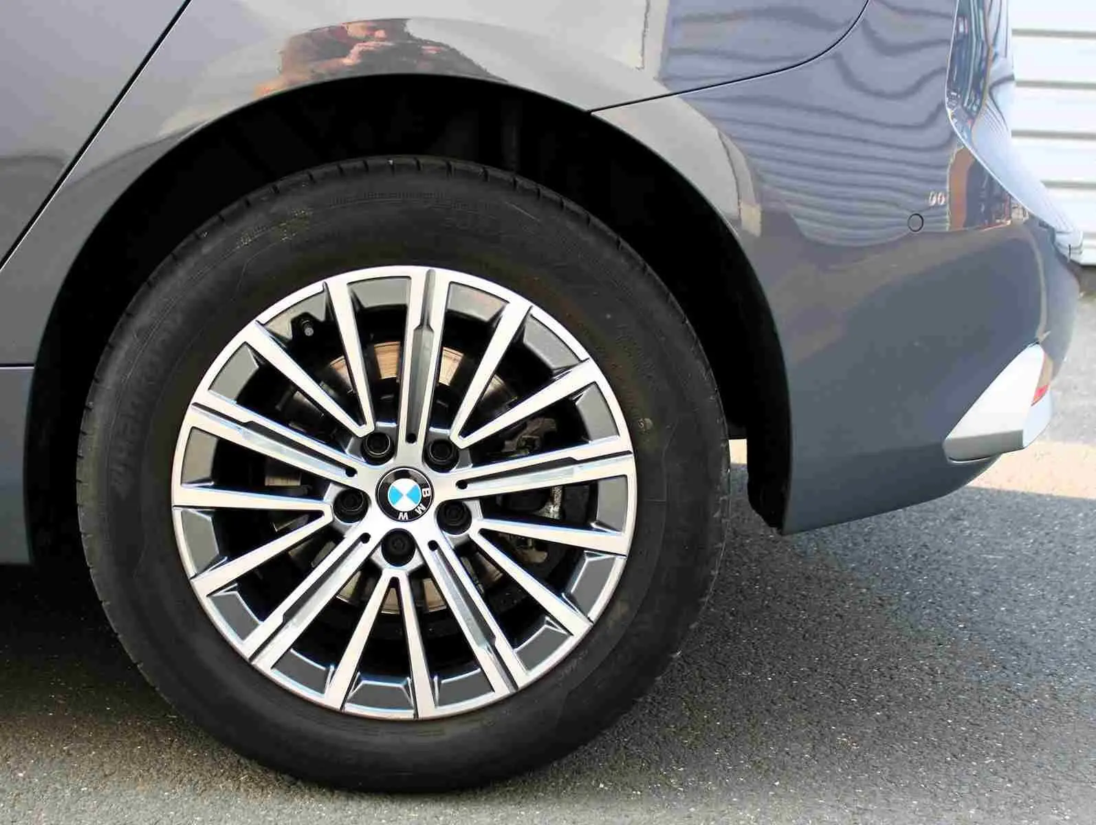 Gros plan sur la roue arrière droite d’une BMW Série 2 Active Tourer gris Nardo métal avec jante alliage multi-branches.