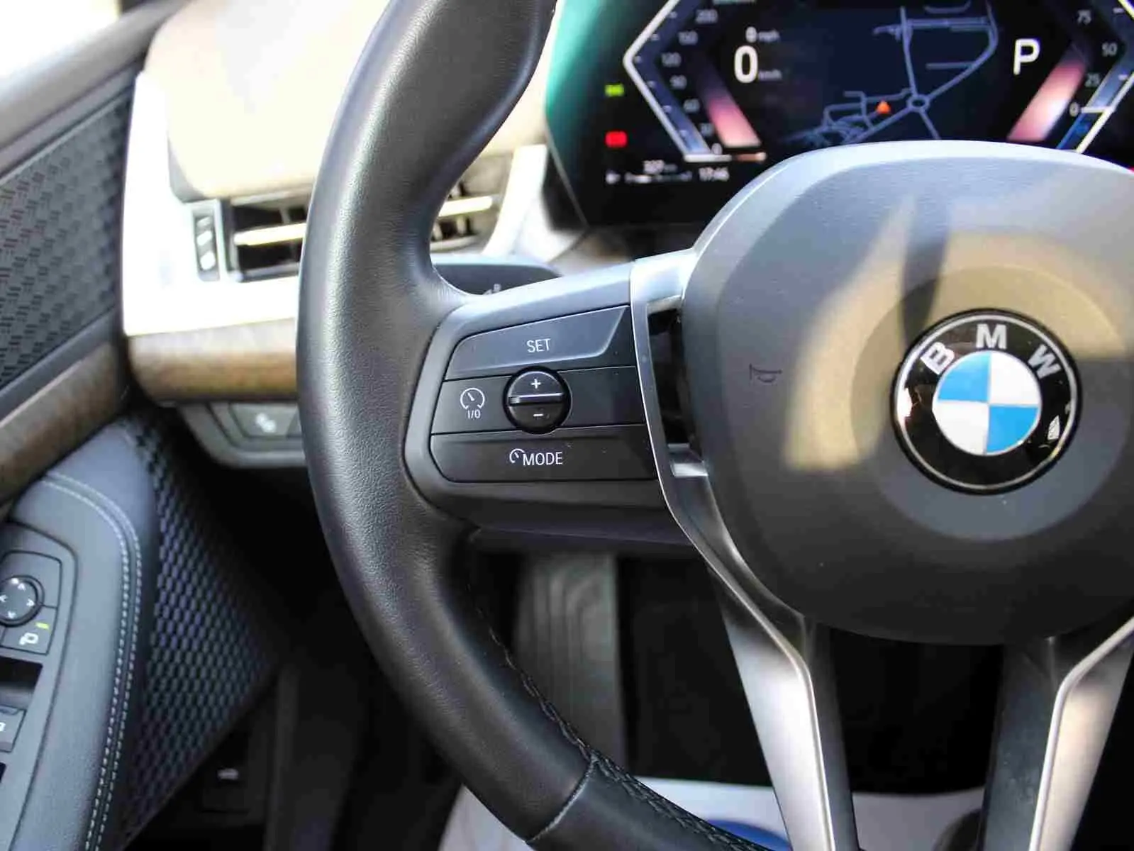 Gros plan sur le volant cuir noir et le tableau de bord digital d'une BMW Série 2 Active Tourer 218d 2023.