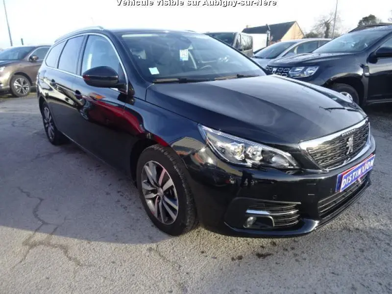 Peugeot 308 SW noire vue en 3/4 avant droit, mettant en valeur ses phares LED et la calandre chromée.