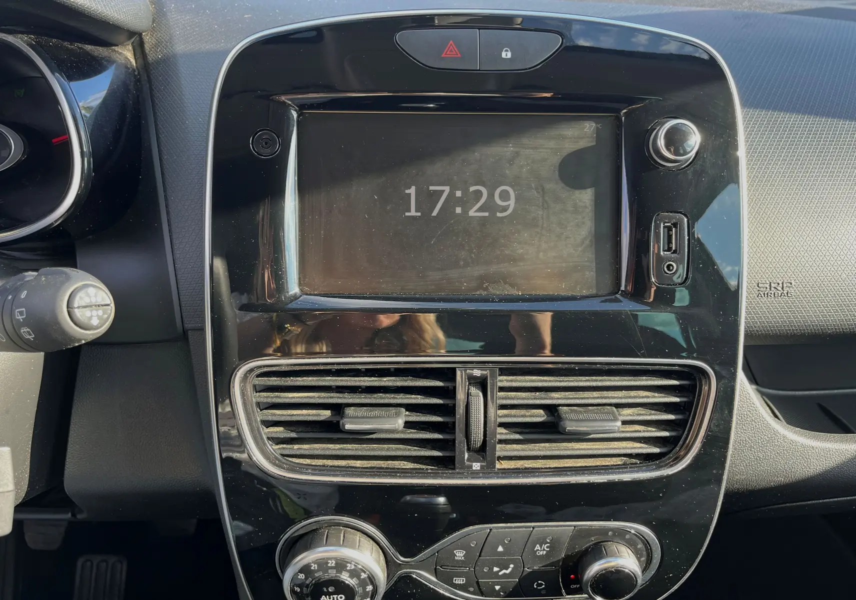 Vue rapprochée du tableau de bord noir brillant de la Renault Clio IV 2019 avec écran tactile et commandes climatisation.