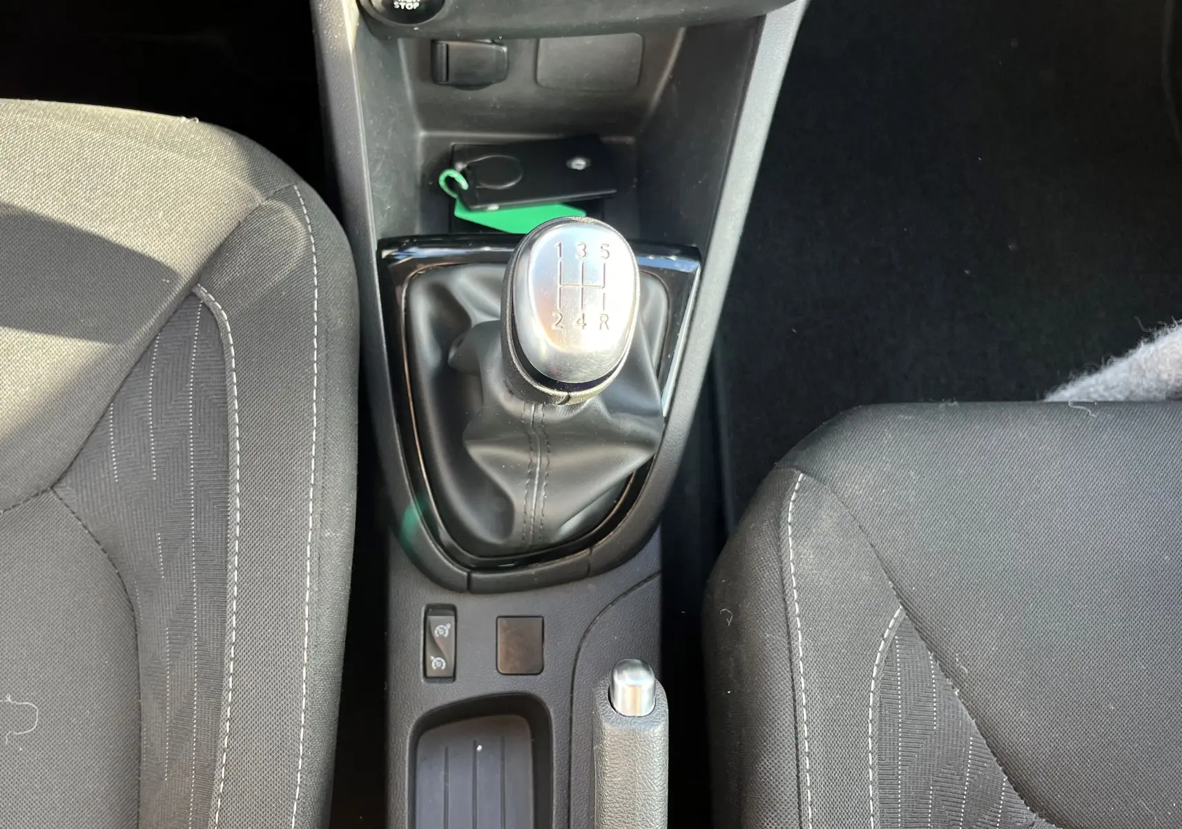 Vue plongeante sur la console centrale d'une Renault Clio IV 2019 avec levier de vitesse manuel et sièges tissu noirs.