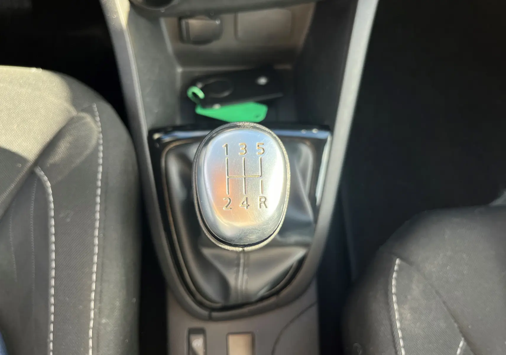 Intérieur côté passager d'une Renault Clio IV 2019, montrant la porte noire avec haut-parleur et partie du siège tissu gris.