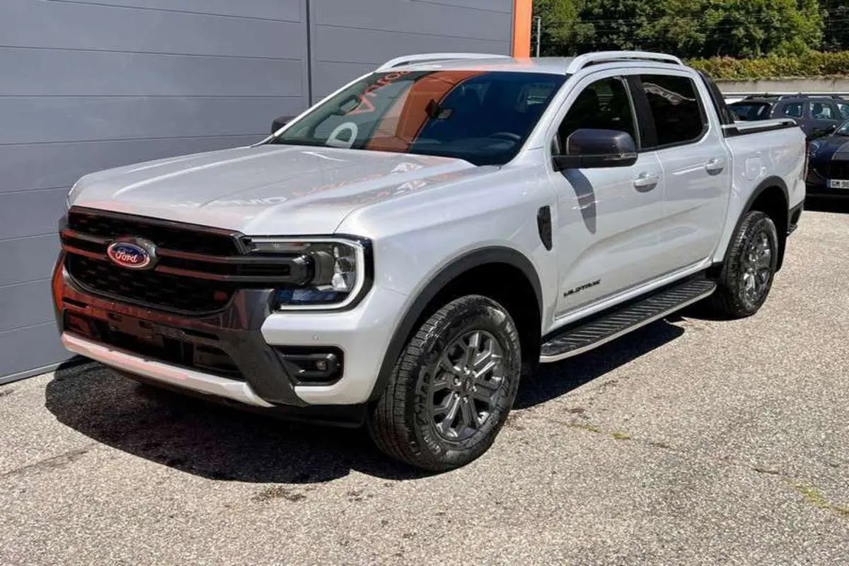 Ford Ranger 2025 gris iconic en 3/4 avant droit, avec calandre noire et jantes alliage foncé Wildtrak Plus.