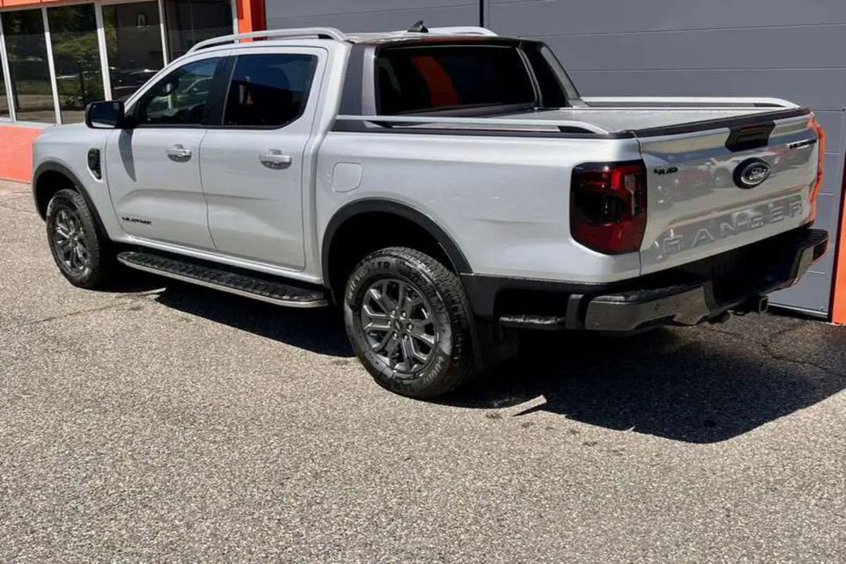 Ford Ranger 3.0 V6 240 Wildtrak Plus gris iconic vu en 3/4 arrière droit avec benne et jantes foncées.
