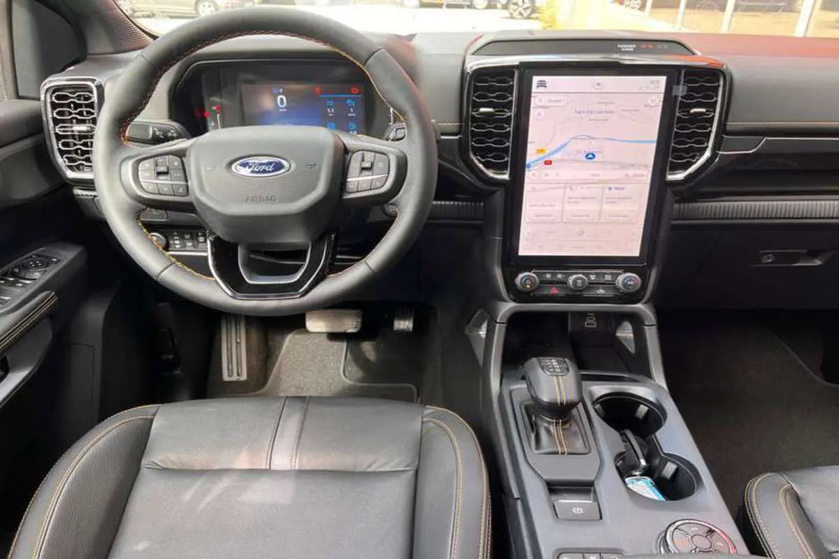 Vue intérieure du Ford Ranger 2025 Wildtrak Plus, tableau de bord avec écran tactile vertical et volant multifonction noir.