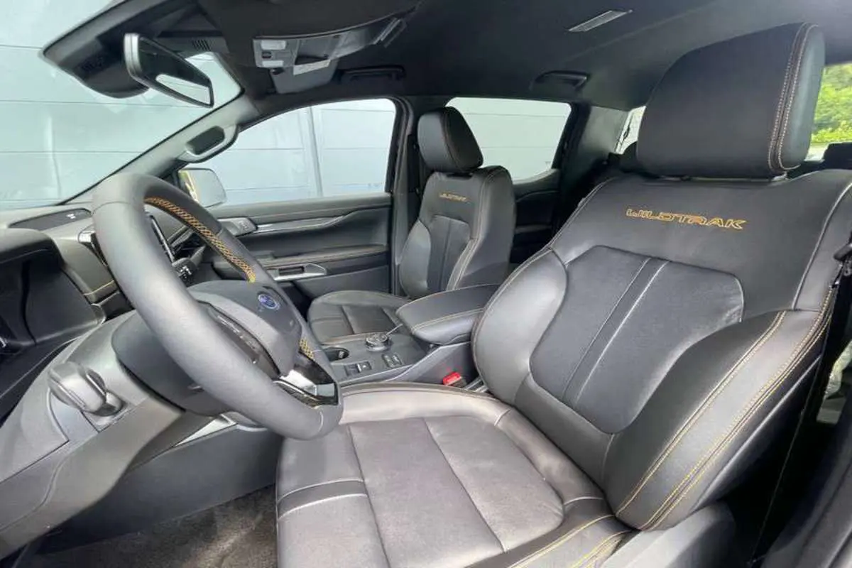 Vue intérieure côté conducteur du Ford Ranger 2025 Wildtrak Plus avec sièges cuir noirs et surpiqûres orange.