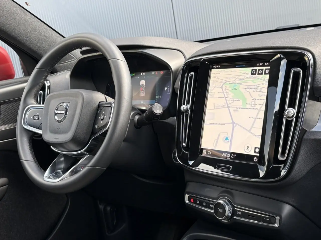 Intérieur du Volvo XC40 2024 vu côté conducteur, avec tableau de bord noir et écran tactile central affichant la navigation.