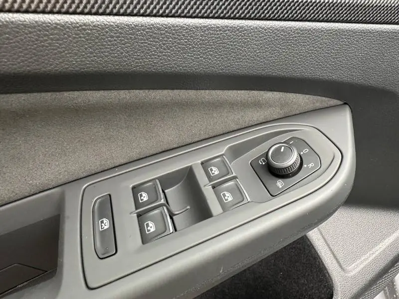 Gros plan sur la commande des vitres et rétroviseurs côté conducteur d’une Volkswagen Golf gris 2.0 TDI R-Line 2026.