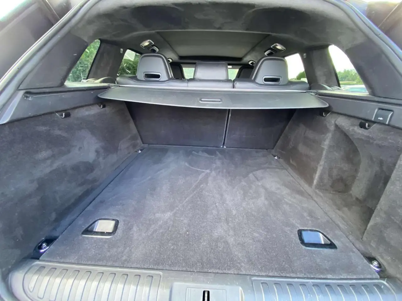 Vue intérieure du coffre spacieux et noir du Range Rover Sport SVR 2016 avec cache-bagages déployé.