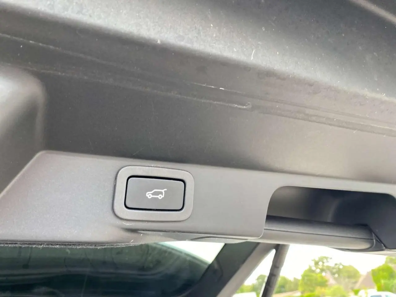 Bouton de commande du hayon électrique sur le bord intérieur du coffre d'un Range Rover Sport noir.
