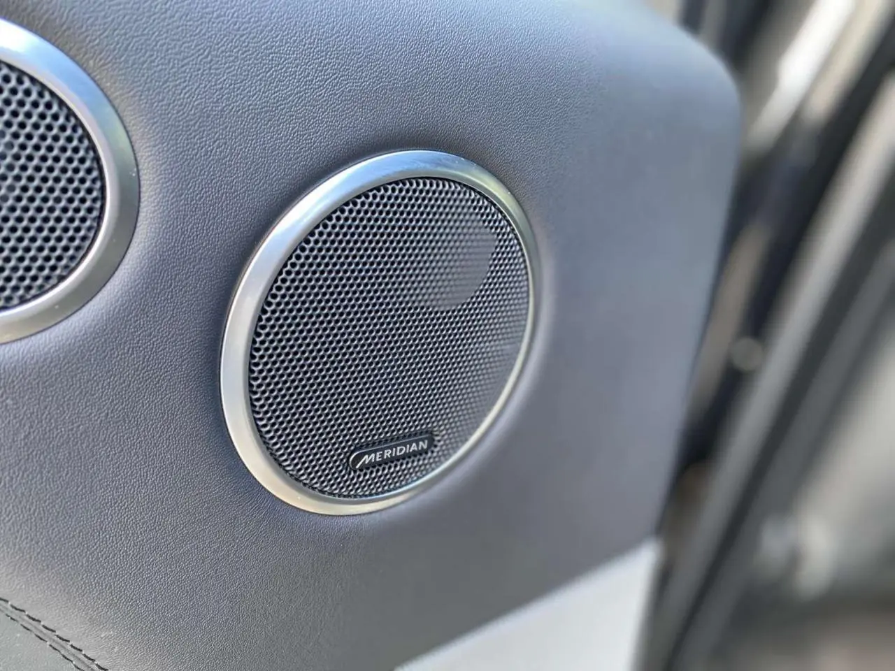 Gros plan sur l'enceinte Meridian intégrée à la porte intérieure du Range Rover Sport noir SVR 2016.