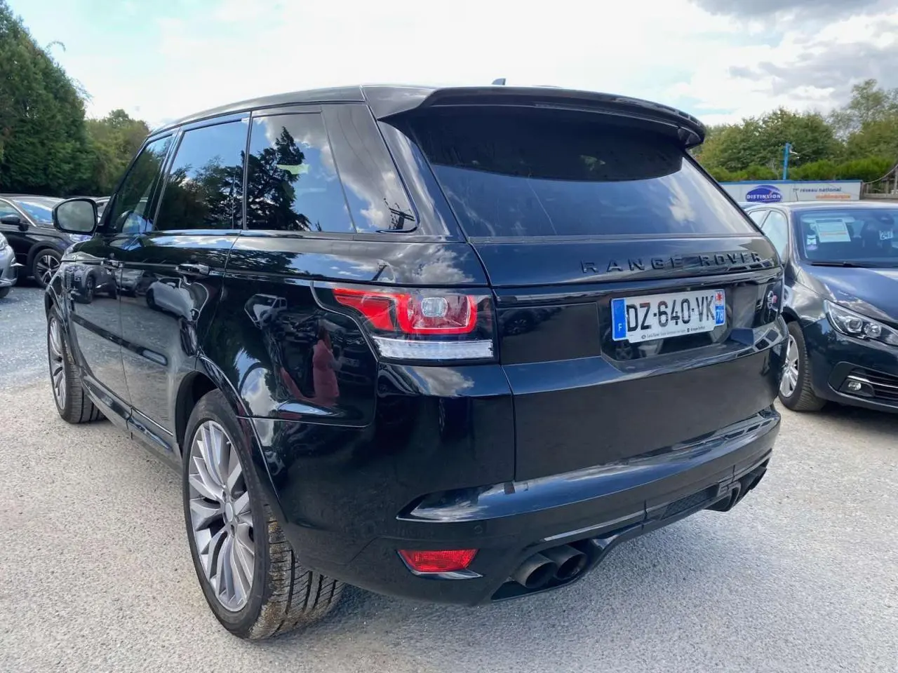 Vue 3/4 arrière droite d'un Range Rover Sport SVR noir avec jantes 22 pouces et quadruple sortie d'échappement.