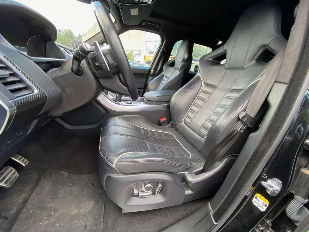 Intérieur noir du Range Rover Sport SVR 2016, vue côté conducteur sur sièges sport en cuir avec logo SVR embossé.