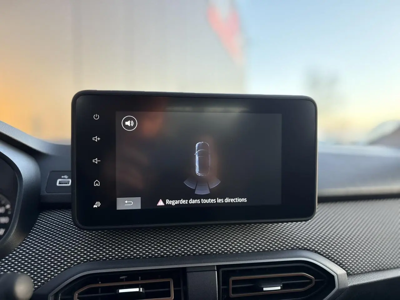 Écran tactile central affichant l'aide au stationnement sur le tableau de bord d'une Dacia Sandero Stepway 2025.