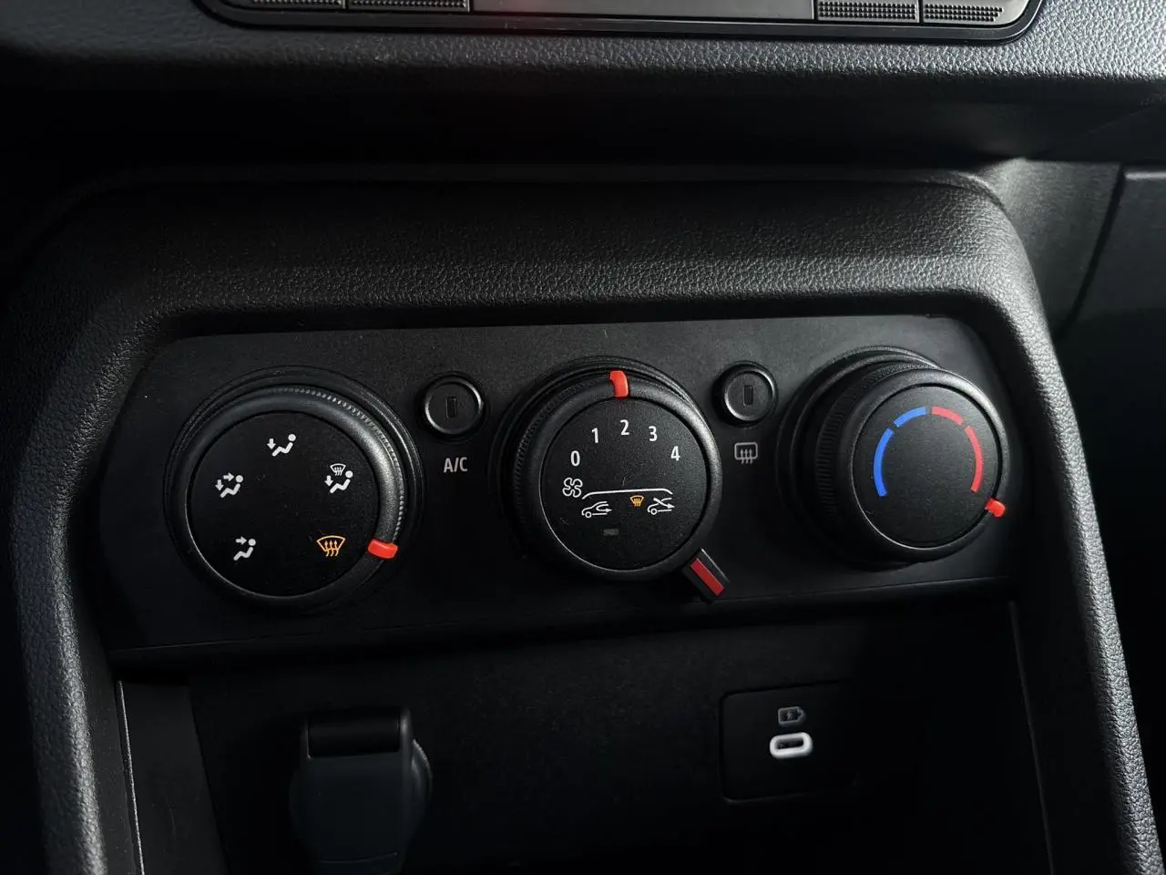 Gros plan sur les commandes de climatisation manuelle noires du tableau de bord de la Dacia Sandero Stepway 2025.