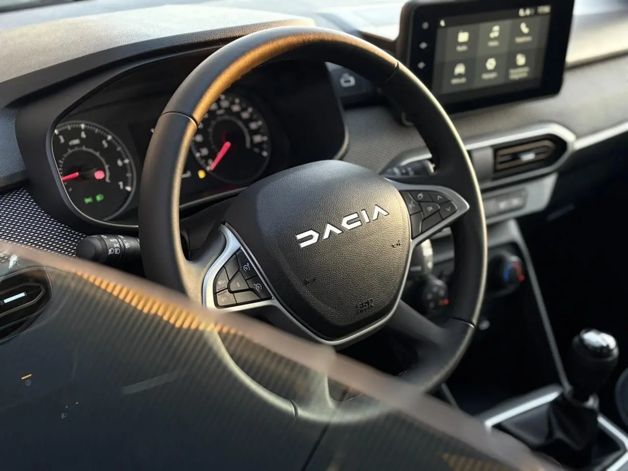 Vue rapprochée du volant noir Dacia avec commandes intégrées et tableau de bord numérique de la Sandero Stepway 2025.