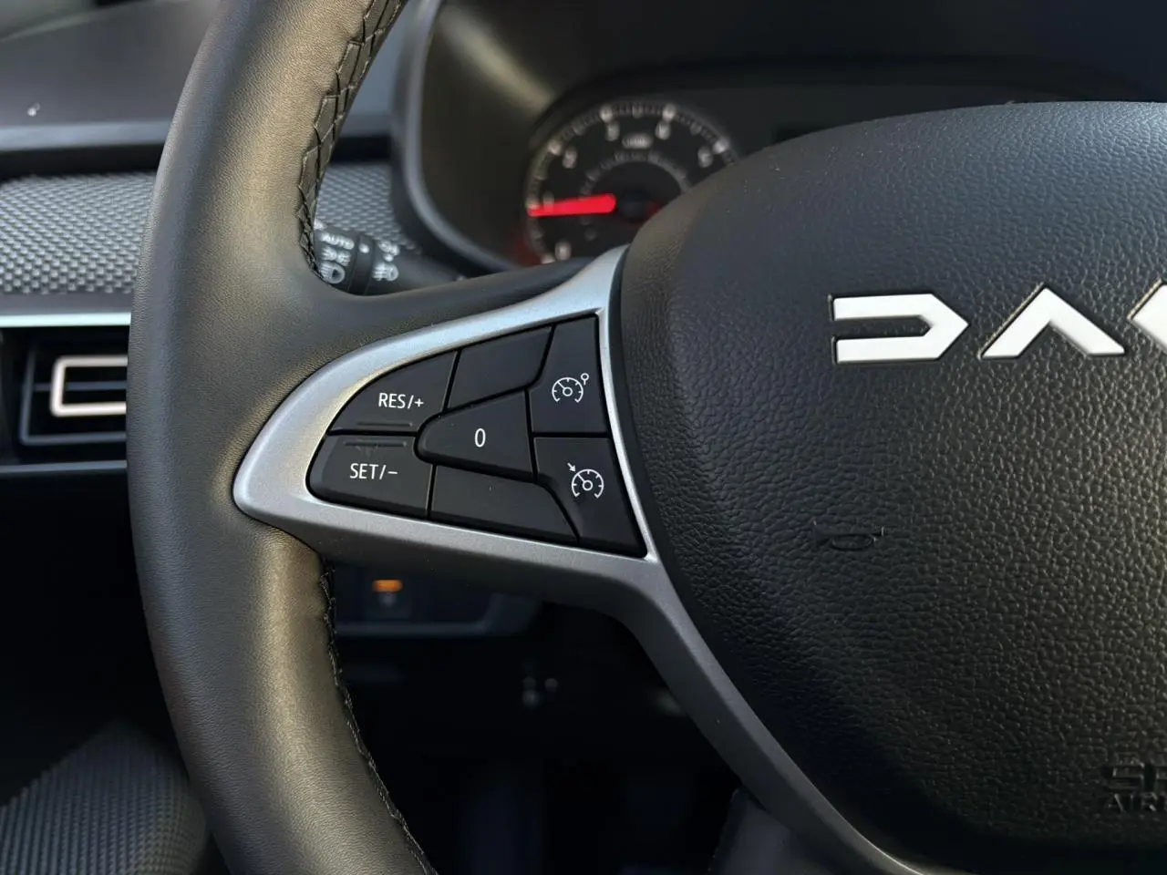 Gros plan sur le volant noir du Dacia Sandero Stepway 2025, avec commandes de régulateur de vitesse côté gauche.