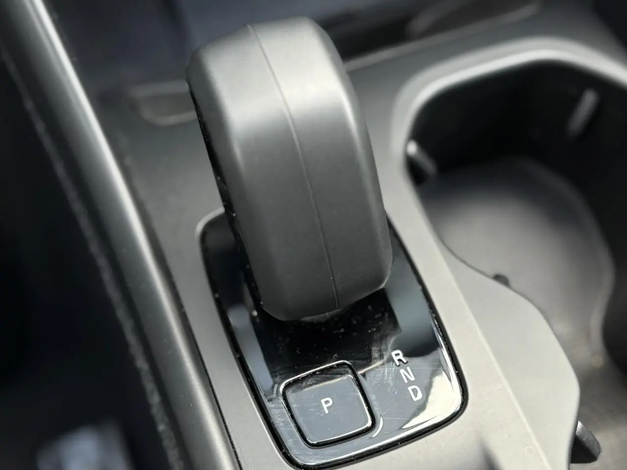 Gros plan sur la commande de boîte automatique noire du Volvo XC40 2024, avec levier et bouton de parking visible.