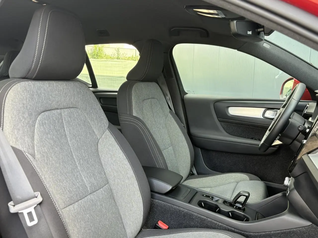 Vue intérieure côté droit du Volvo XC40 2024 avec sièges gris clair et volant noir visible.