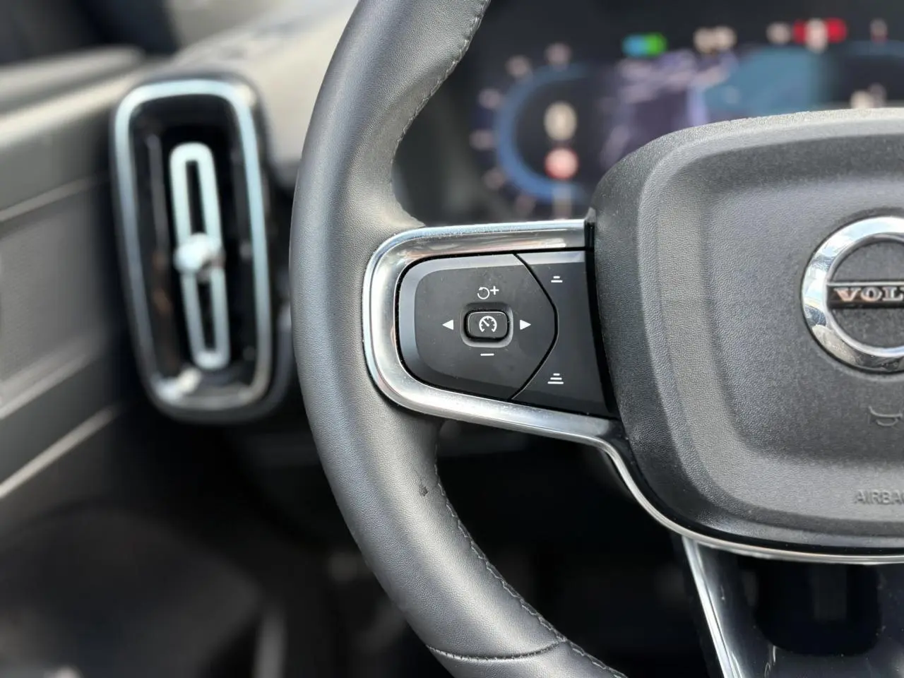 Gros plan sur la partie gauche du volant noir du Volvo XC40 2024 avec commandes de régulateur de vitesse.