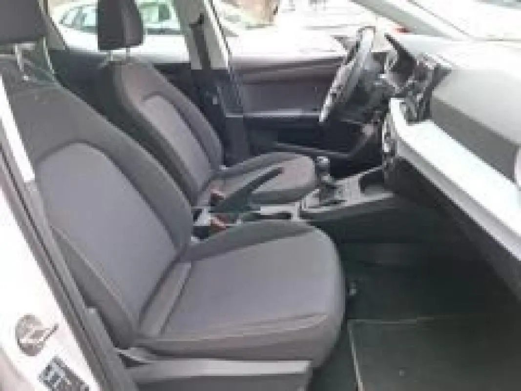 Intérieur côté gauche de la SEAT Ibiza blanche 2023, montrant les sièges avant et le tableau de bord moderne.