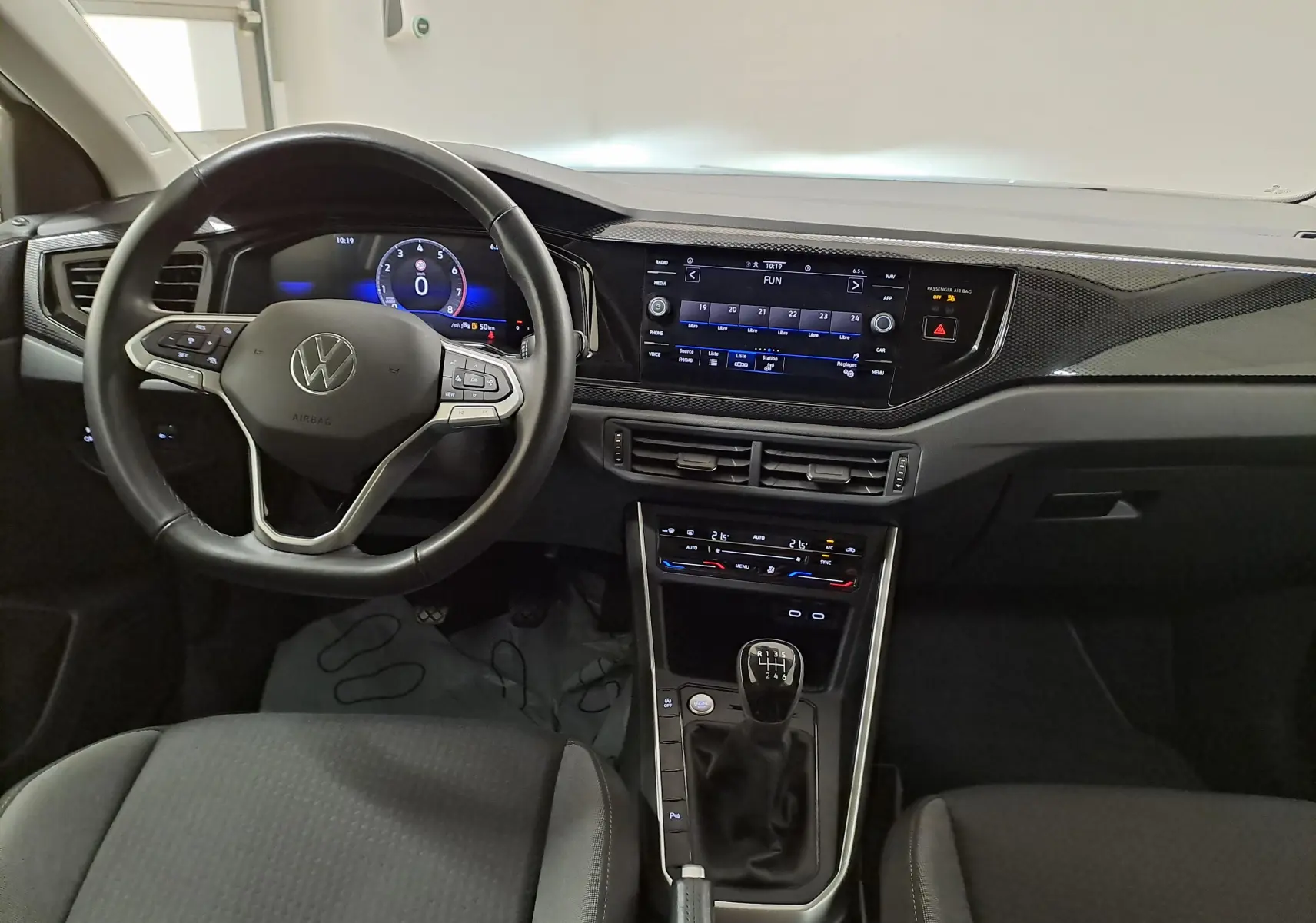 Vue intérieure avant du Volkswagen Taigo 2024 avec volant multifonction, écran tactile et levier de vitesses manuel.